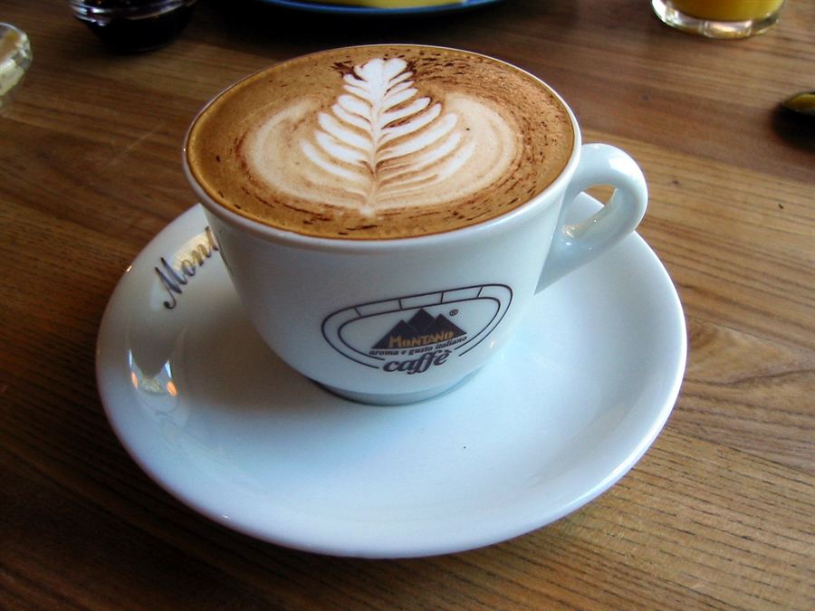 Freshly pulled latte with rosetta art in a warm ceramic cup on a saucer