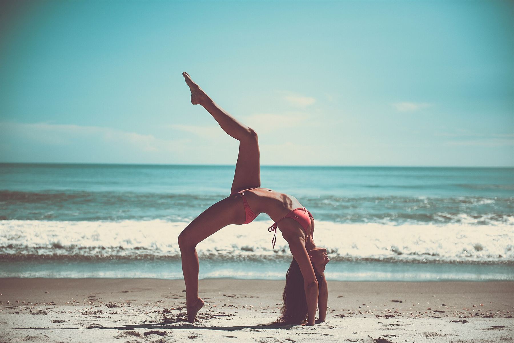 Sunlight streams gently into a serene yoga studio space with polished wooden floors and natural linen curtains