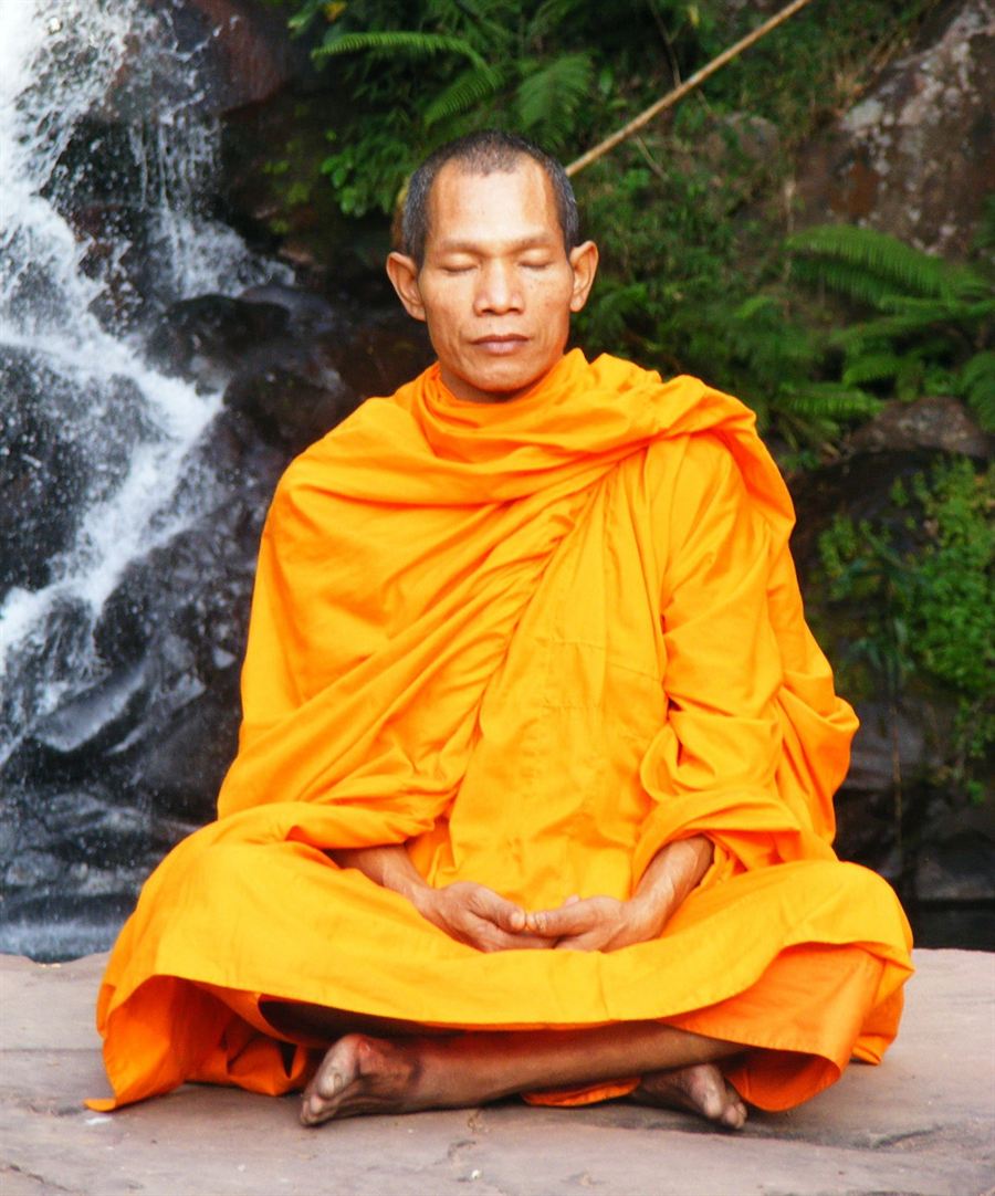 Hands resting gently on crossed knees during a seated meditation in a soft-lit studio